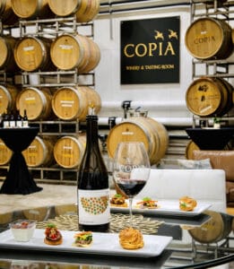 Wine and food pairing at Copia Winery tasting room with barrels.