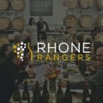 a group of people around a table with wine bottles