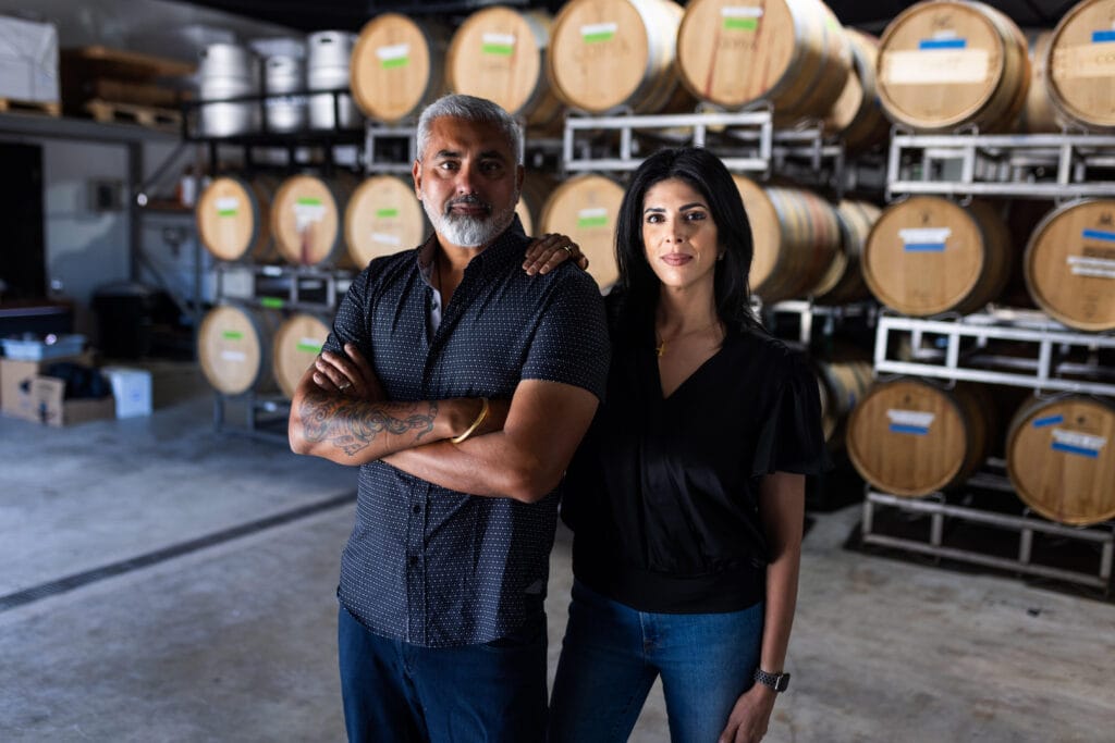 a man and a woman standing in a barrel room of a winery